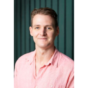 Headshot of Mike Trott smiling with a green background