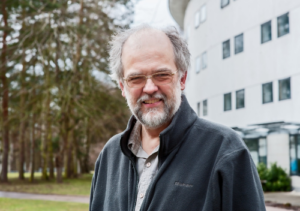 Professor Paul Hunter smiling standing in front of hospital building
