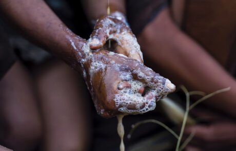 A San Bushmen woman using the pulp from a tuber root to makesoap for washing her hands and face
