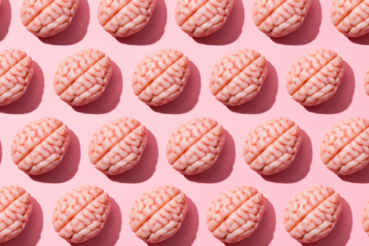 Pattern of small pink model brains arranged in rows on a pale pink background. Pattern of small pink model brains arranged in rows on a pale pink background.