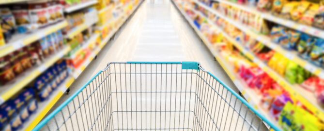 A shopping cart by a store shelf in a supermarket