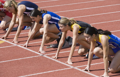 Female athletes in starting blocks, ready to run