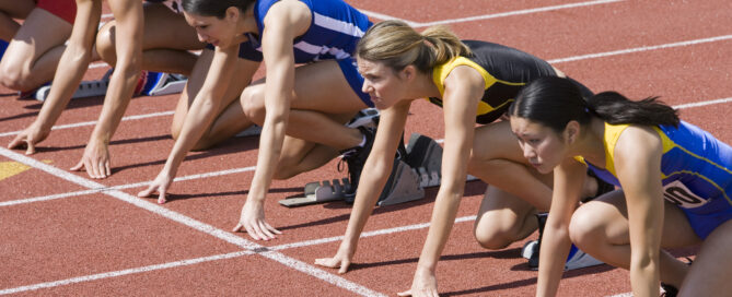 Female athletes in starting blocks, ready to run