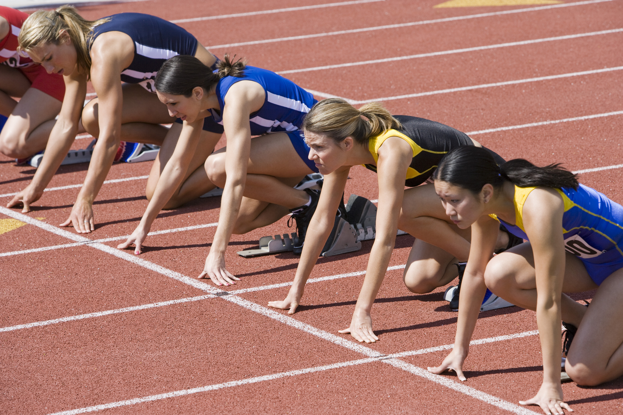 Female athletes in starting blocks, ready to run
